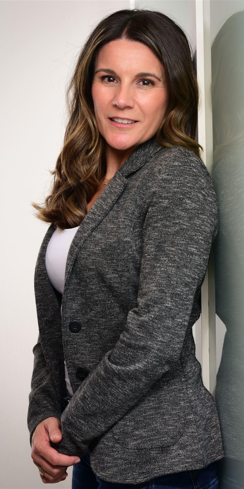 Samantha Munive, Teammitglied bei Kienast Leadership Consulting, im professionellen Portrait mit grauem Blazer und freundlichem Ausdruck vor hellem Hintergrund