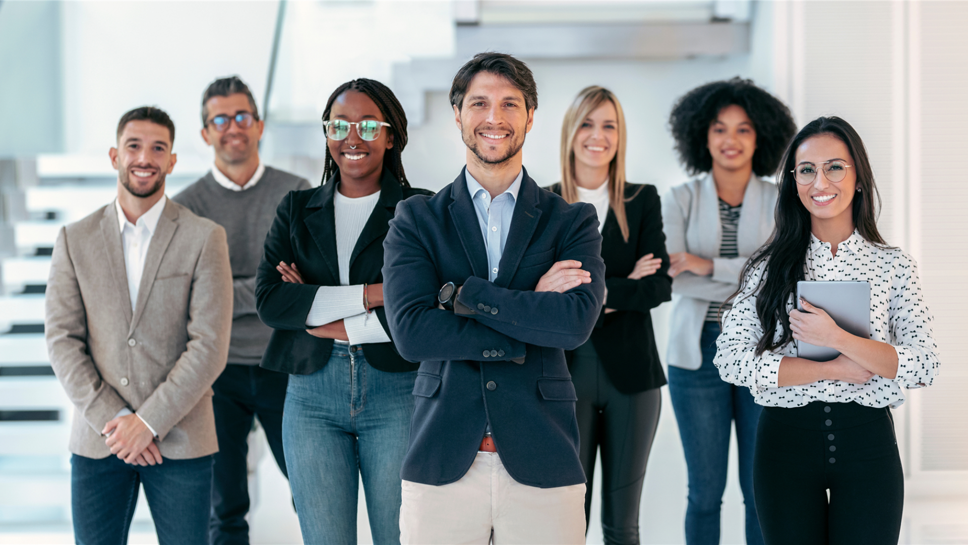 Junge, diverse Gruppe angehender Führungskräfte in Business-Kleidung steht selbstbewusst und lächelnd im modernen Büro – symbolisiert zukünftige Leadership-Kompetenz und Potenzialentwicklung