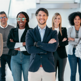 Junge, diverse Gruppe angehender Führungskräfte in Business-Kleidung steht selbstbewusst und lächelnd im modernen Büro – symbolisiert zukünftige Leadership-Kompetenz und Potenzialentwicklung