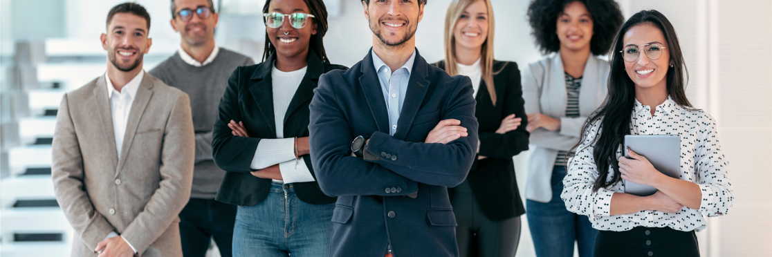 Junge, diverse Gruppe angehender Führungskräfte in Business-Kleidung steht selbstbewusst und lächelnd im modernen Büro – symbolisiert zukünftige Leadership-Kompetenz und Potenzialentwicklung