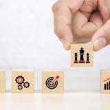 Holzbausteine mit Symbolen für Idee, Prozess, Ziel, Strategie und Wachstum – symbolisieren die Entwicklung und Umsetzung einer erfolgreichen HR-Strategie