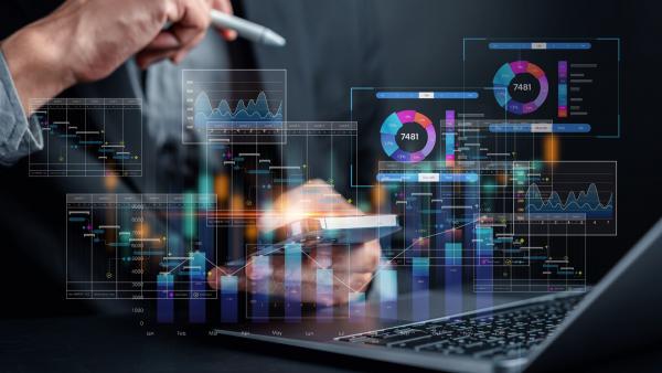 Geschäftsperson analysiert digitale Diagramme und Statistiken auf Laptop und Smartphone, symbolisiert datenbasierte strategische Planung und Konzeptentwicklung