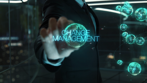 Businessperson berührt eine digitale Hologramm-Kugel mit der Aufschrift 'Change Management'