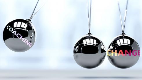 Silberne Pendelkugeln mit den Wörtern 'Coaching' und 'Change' symbolisieren Impulse für Veränderung durch professionelles Executive Coaching