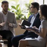 Führungskraft im Gespräch mit einem kleinen Team während einer Coaching-Sitzung, symbolisiert vertrauensvolle Kommunikation und persönliche Weiterentwicklung im Leadership Coaching