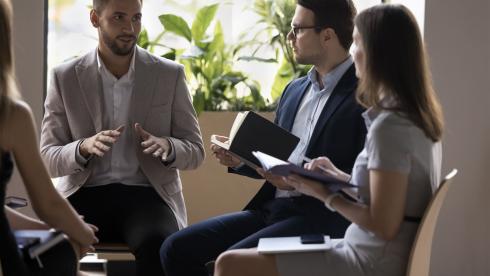 Führungskraft im Gespräch mit einem kleinen Team während einer Coaching-Sitzung, symbolisiert vertrauensvolle Kommunikation und persönliche Weiterentwicklung im Leadership Coaching