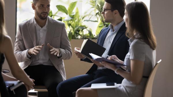 Führungskraft im Gespräch mit einem kleinen Team während einer Coaching-Sitzung, symbolisiert vertrauensvolle Kommunikation und persönliche Weiterentwicklung im Leadership Coaching